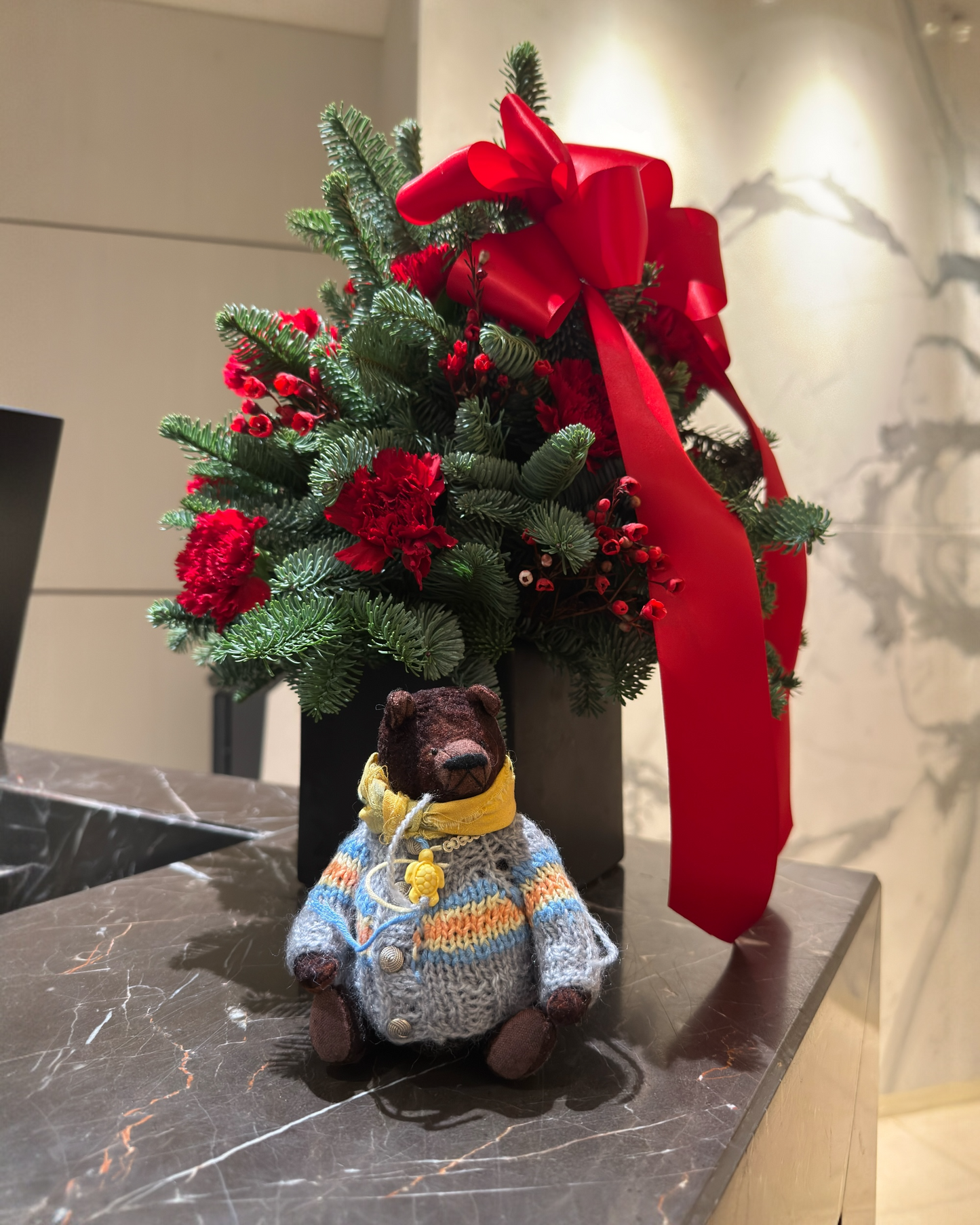 Miniature bear with Christmas floral arrangement in Hong Kong hotel lobby